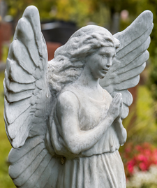 Angel Statue Praying In Front Of Several Tombstones On A Graveya
